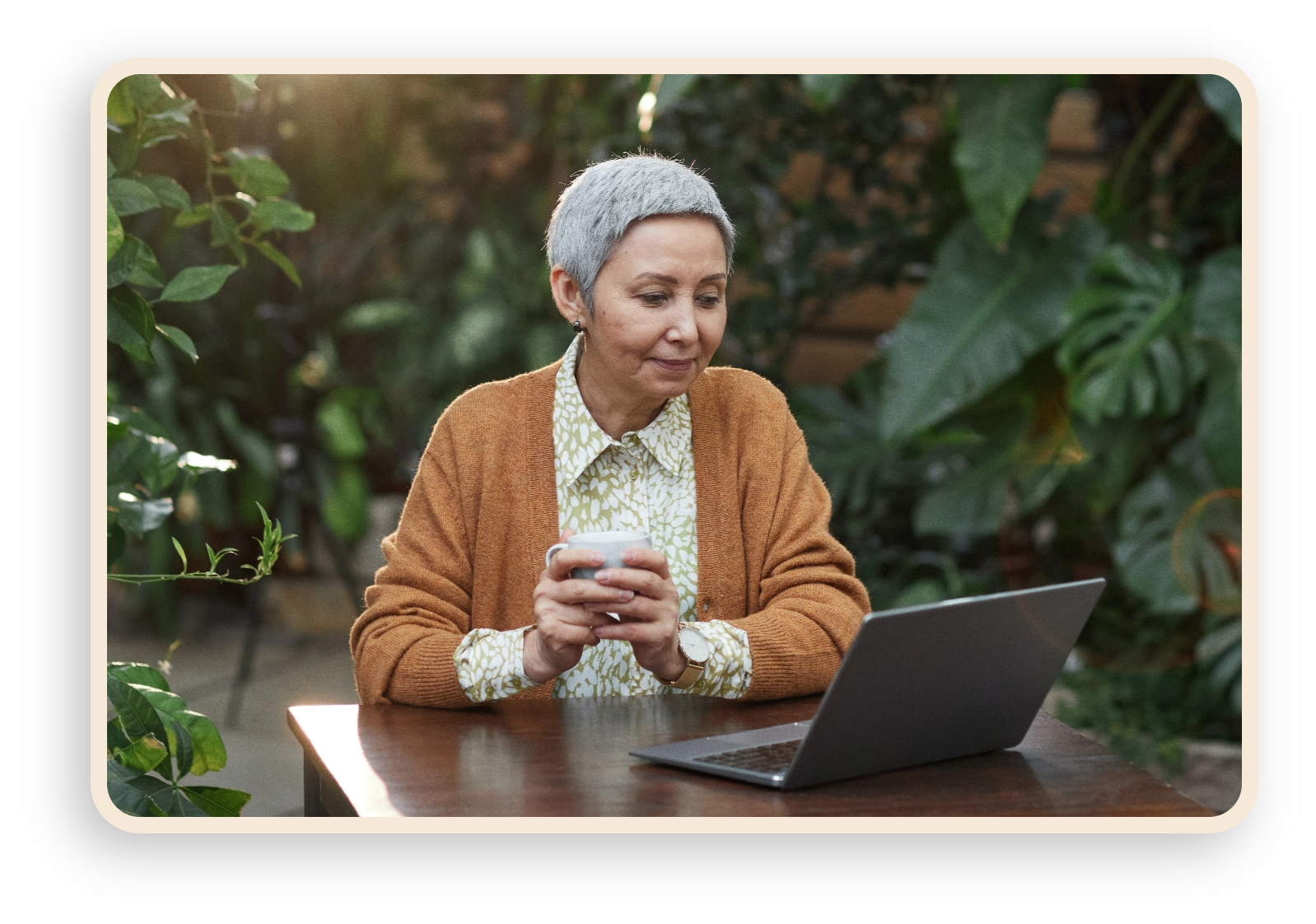older woman drinking coffee and looking at computer